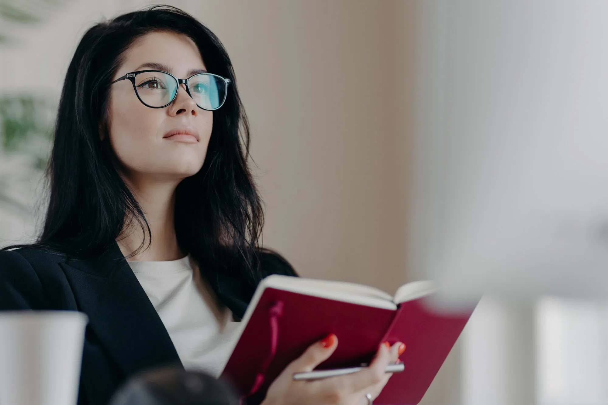 beautiful woman with thoughtful expression holds opened notepad writes time management